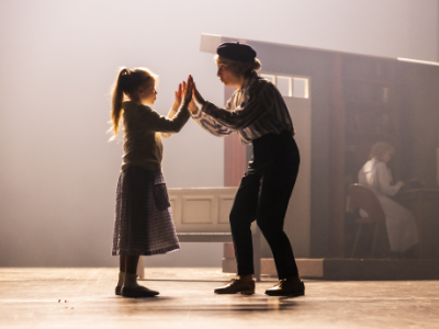 Eine älterere Frau und ein kleines Mädchen stehen auf der Bühne und halten beide Hände aneinander.